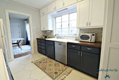 a kitchen with black cabinets and white appliances in the corner, along with a rug on the floor