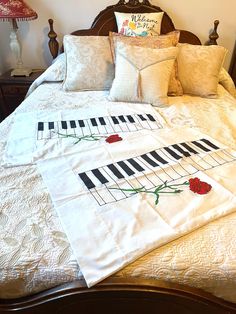 a white sheet with piano keys and roses on it is sitting on a wooden bed