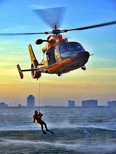 a man is being pulled into the water by a helicopter