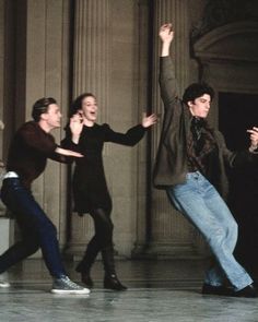 three young men are dancing in front of columns