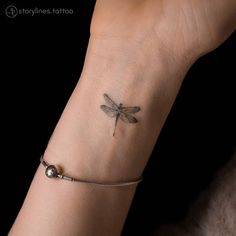 a woman's wrist with a dragonfly tattoo on her left arm and a beaded bracelet around the wrist