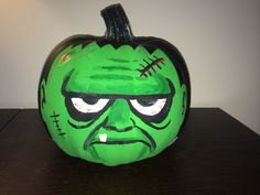 a green painted pumpkin sitting on top of a wooden table