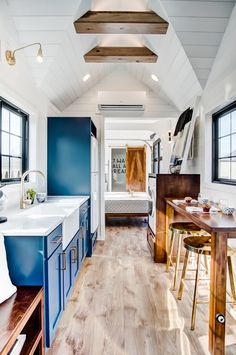 a kitchen and dining area in a tiny home with blue walls, wood flooring and white ceiling