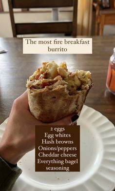 a person holding up a piece of food on top of a white plate with words above it that read, the most fire breakfast burrito