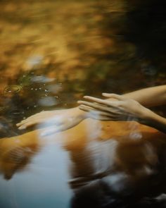 two hands reaching out to touch each other's hand in the reflection of water