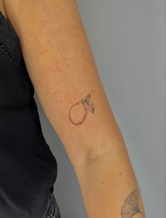 a woman's arm with a small apple tattoo on the left side of her arm