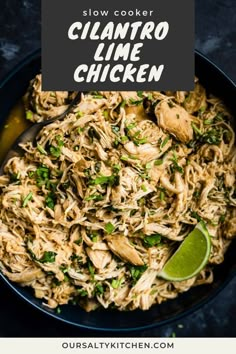 a black bowl filled with noodles and garnished with cilantro, parsley and lime