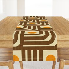 a wooden table topped with a brown and orange patterned table runner on top of a wooden table