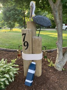 a bird sitting on top of two wooden posts with numbers and a blue striped tube