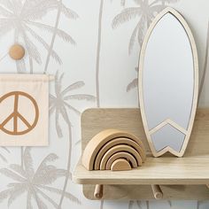 a wooden shelf with a mirror, coasters and peace sign on it next to a palm tree wallpaper