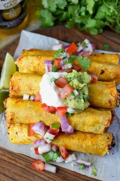 some tacos are sitting on a piece of paper with guacamole and sour cream