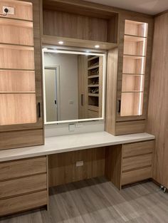 an empty dressing room with wooden cabinets and white counter tops, lighted by recessed lighting