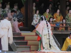 A man and a group of women dressed in heian robes.