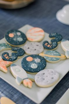 some cookies are on a white plate with blue and orange designs in the shape of planets