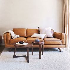 a living room with a brown leather couch and coffee table in front of a window