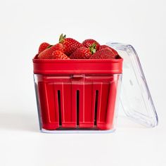 a plastic container filled with strawberries on top of a white table