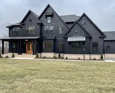 a large black house sitting on top of a lush green field