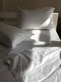 a bed with white sheets and pillows on it