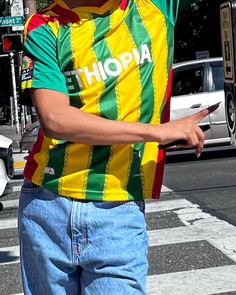 a man in a colorful shirt is crossing the street with his hand up to his head