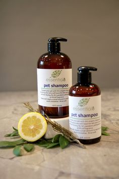 two bottles of pet shampoo sitting on top of a table next to a lemon