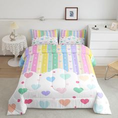 a bed with colorful hearts on it in a room next to a white table and chair