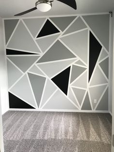 an empty room with a ceiling fan and wallpaper on the walls in black and white