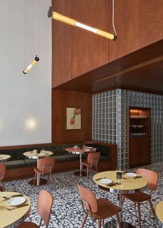 an empty restaurant with wooden tables and chairs in front of wood paneled walls, along with patterned flooring