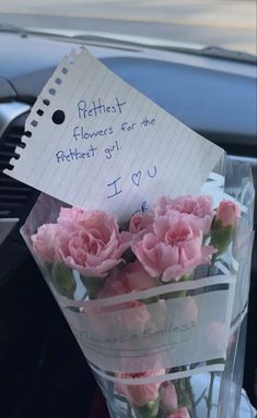 pink carnations are wrapped in clear cellophane and placed on a note attached to the windshield