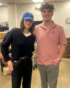 a young man and woman standing next to each other in a room with boxes on the floor