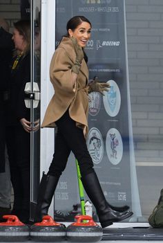 a woman in black boots and a tan coat