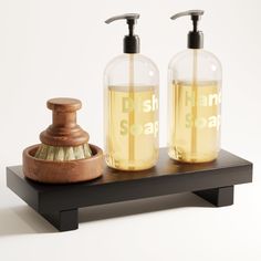 two soap dispensers sitting on top of a wooden stand next to each other