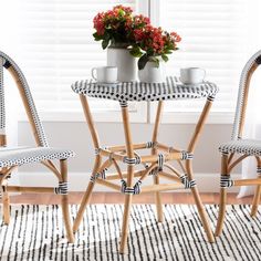 two chairs and a table in front of a window with potted flowers on it