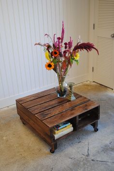 a coffee table with flowers in a vase on top of it, sitting next to a door