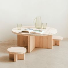 a wooden table with two stools and a book on the table next to it