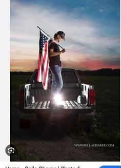 a woman standing on the back of a truck holding an american flag