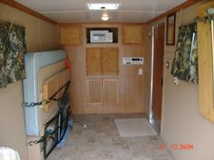 the inside of an rv with wood paneling and curtains on the windows, door to another room