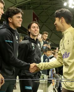 two men shaking hands in front of an audience at a sporting event with other people