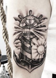 a black and white photo of a lighthouse tattoo on the left upper half of the arm