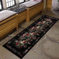 a black area rug with flowers on it in front of two sinks and window sill