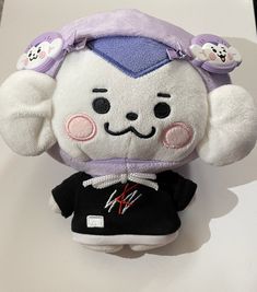 a stuffed animal wearing a purple hat and black shirt with ears on it's head