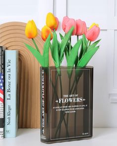 a vase with flowers in it sitting on a table next to books and a book