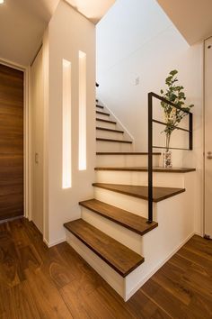 there is a plant that is on the top of some stairs in this house with wood floors and white walls