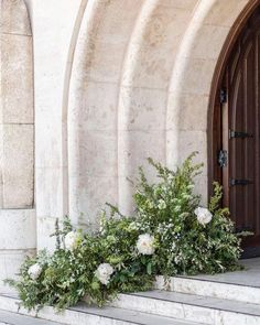 two white flowers are sitting on the steps in front of an arched door and doorway