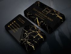 two black and gold business cards sitting on top of a table next to each other