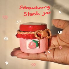 a hand holding a small jar with food in it and the words strawberry stash jar above it