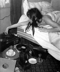 a woman laying in bed next to an old record player