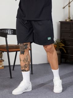 a man with tattoos on his arm and leg is standing in front of a chair