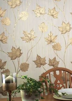 a wooden table topped with a vase filled with flowers next to a wallpapered wall