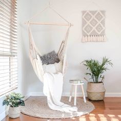 a hammock hanging from the ceiling in a room with wood floors and white walls