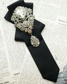 a black tie with some brooches on it and an old book in the background